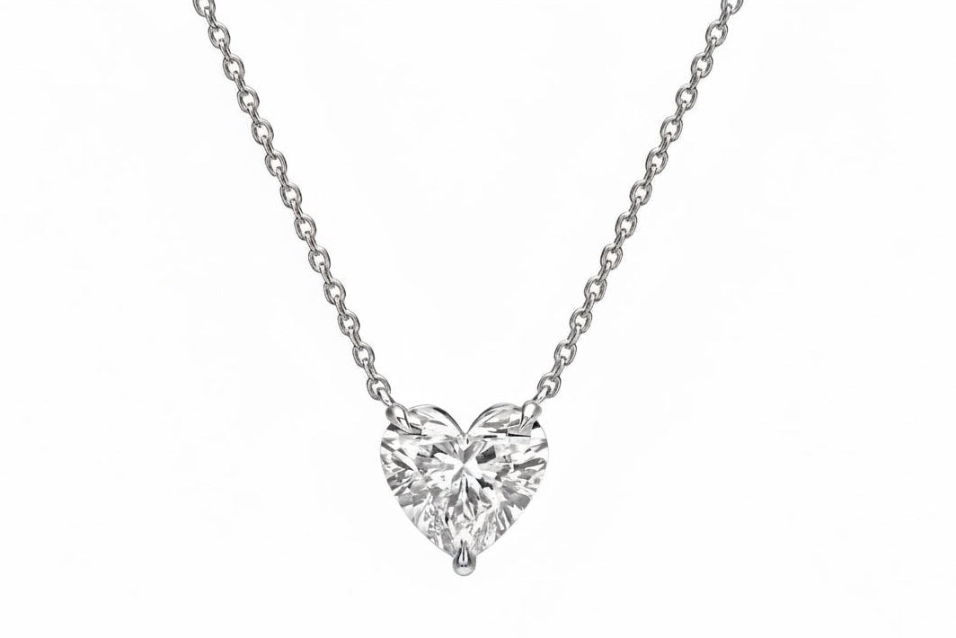 Heart-shaped diamond pendant on a chain against a white background